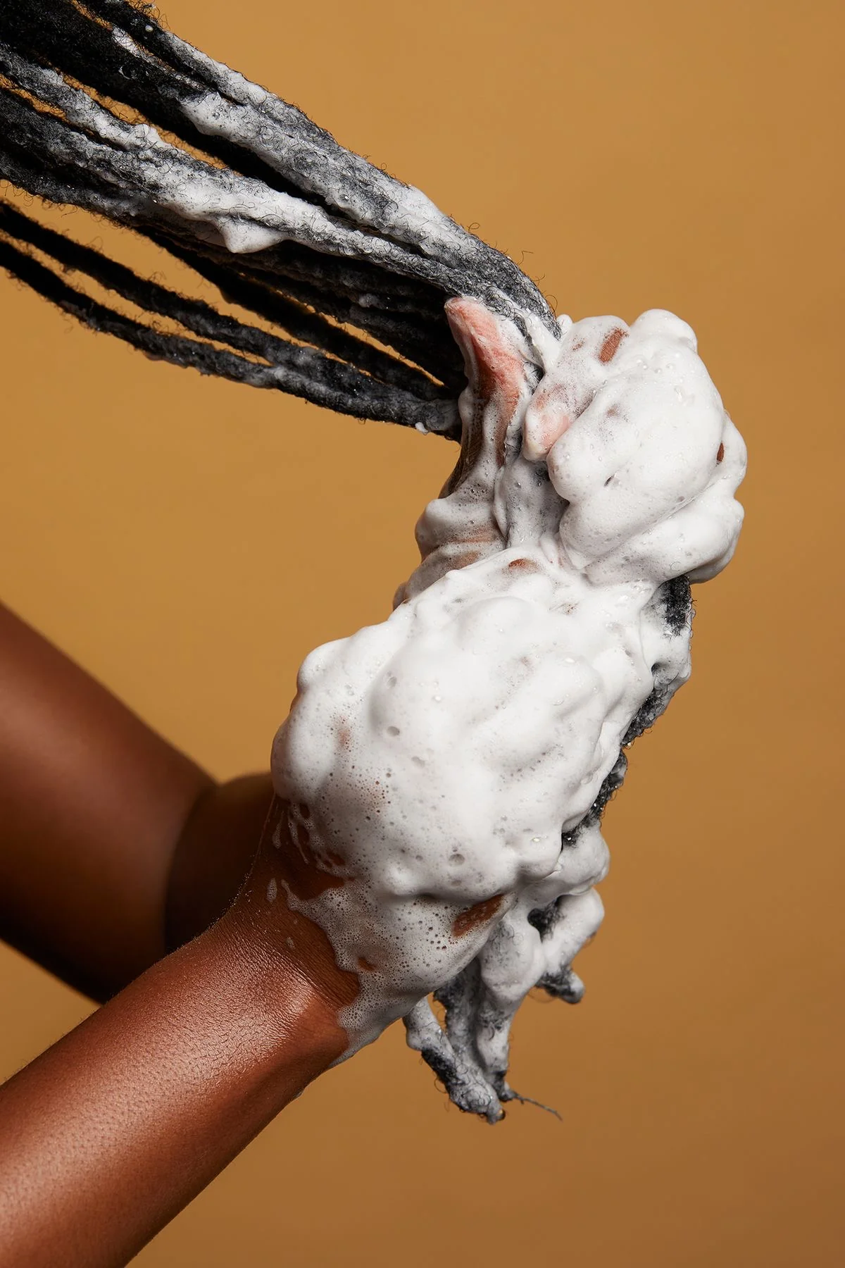 Locs being lathered by hand during a wash